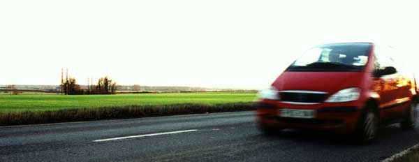 A red car being driven on an open road